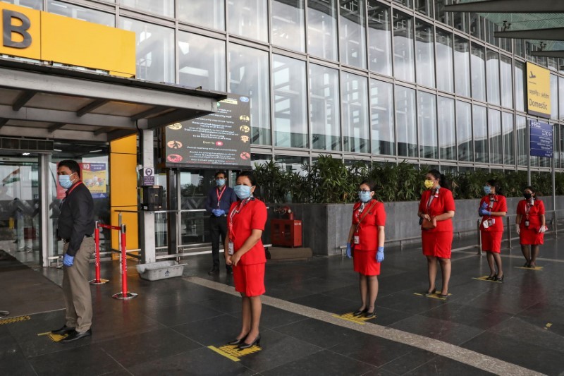 Air Asia staff members stand on social distancing markings, as they wait to enter Netaji Subhas Chandra Bose International Airport (CCU), after the government allowed domestic flight services to resume, during an extended nationwide lockdown to slow the spread of the coronavirus disease (COVID-19), in Kolkata, May 27, 2020. REUTERS/Rupak De Chowdhuri